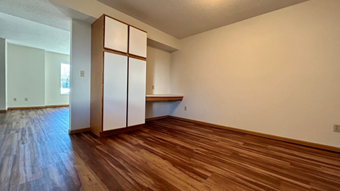 an empty living room with wood floors and a white refrigerator