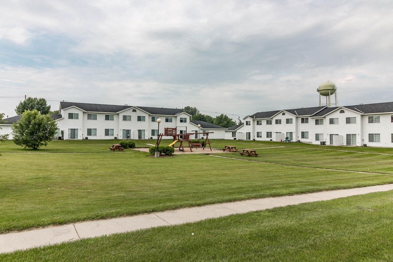 a park with a playground in front of a white building