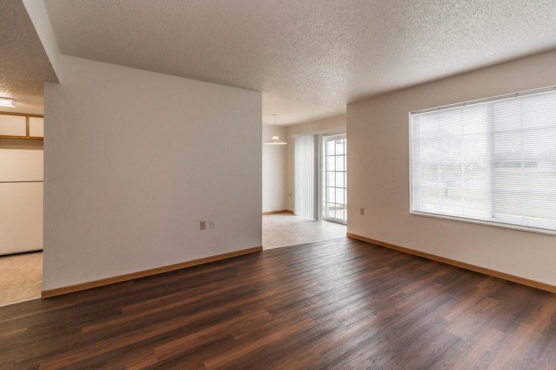 the living room and dining room of an empty house with wood floors and a window