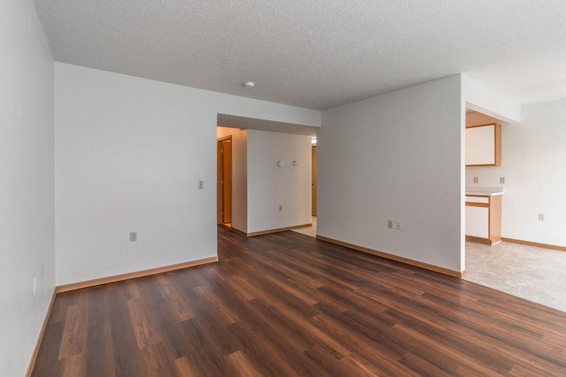 the living room and dining room of an empty house with wood floors and white walls