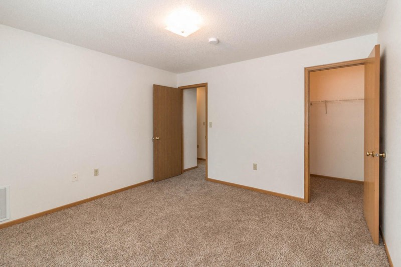 an empty bedroom with two doors and a closet