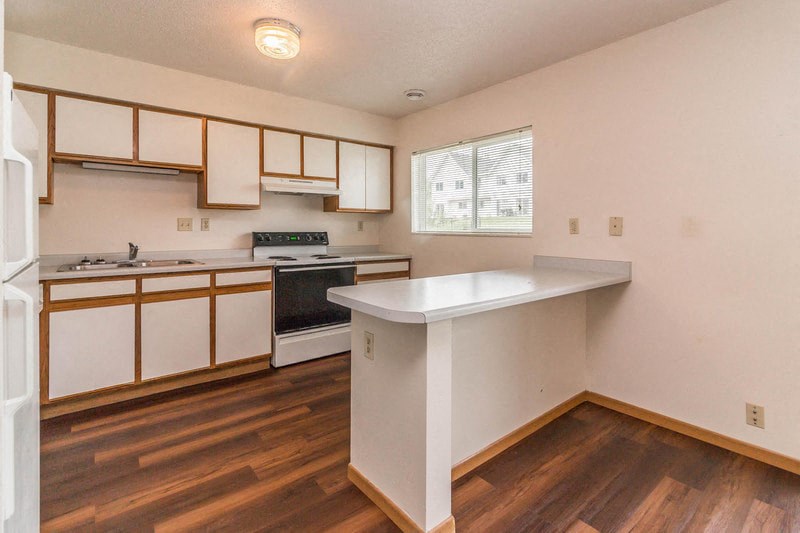 an empty kitchen with white cabinets and a counter top