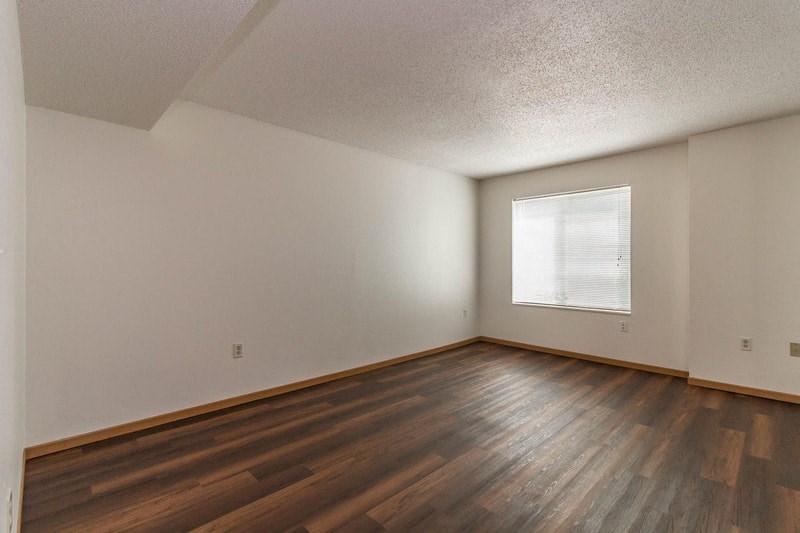 the living room of an empty house with wood floors and a window