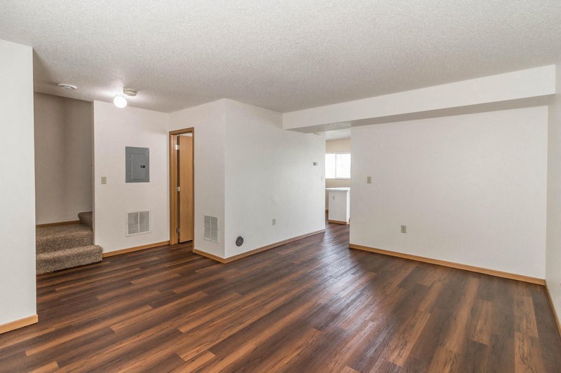 the living room and dining room of an empty house with wood floors and white walls