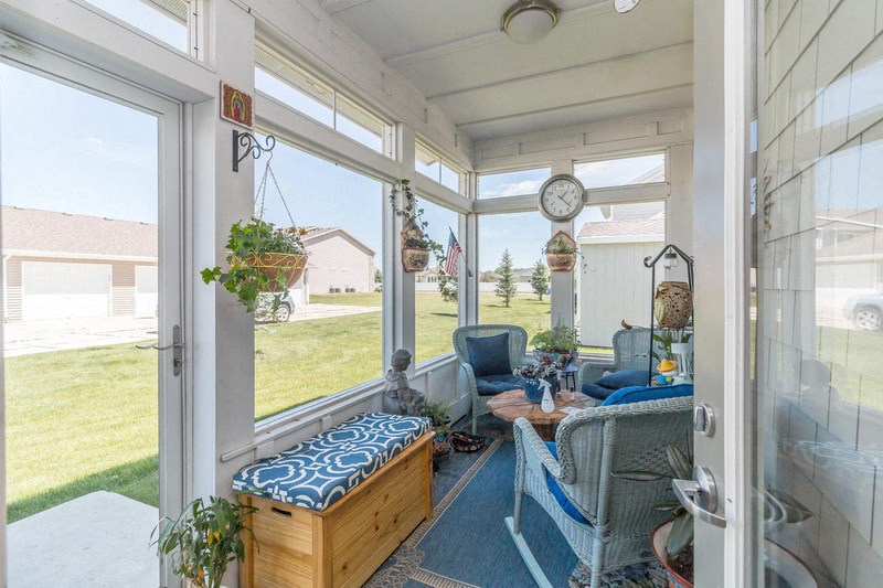 a screened porch with blue chairs and a clock on the wall