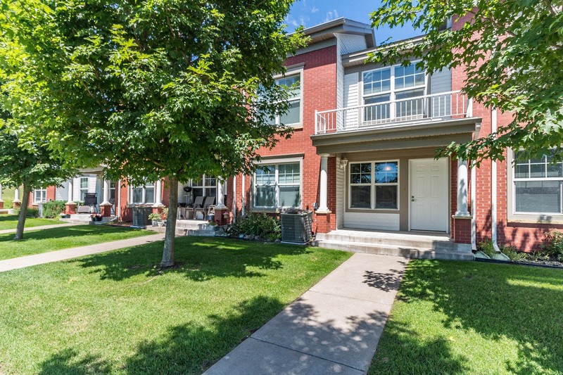 a sidewalk in front of a brick house with trees