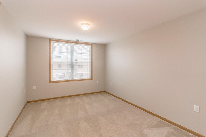 the living room of a home with a large window and a tiled floor