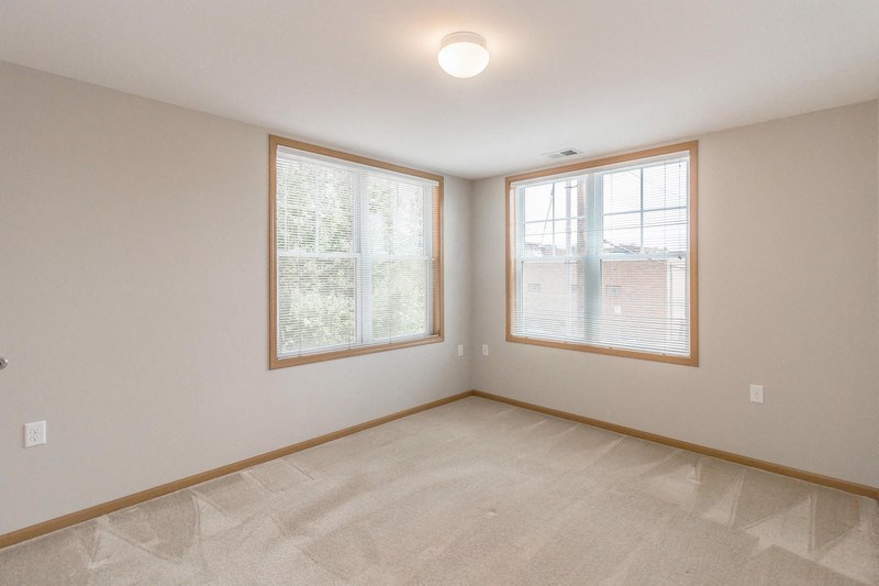 the living room of an empty home with two windows