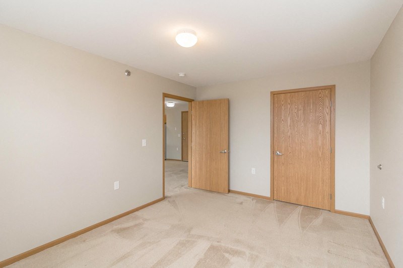 a bedroom with a door to a hallway and a closet