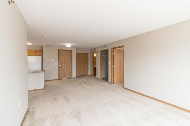 the living room and kitchen of an empty house with white walls and tile floors