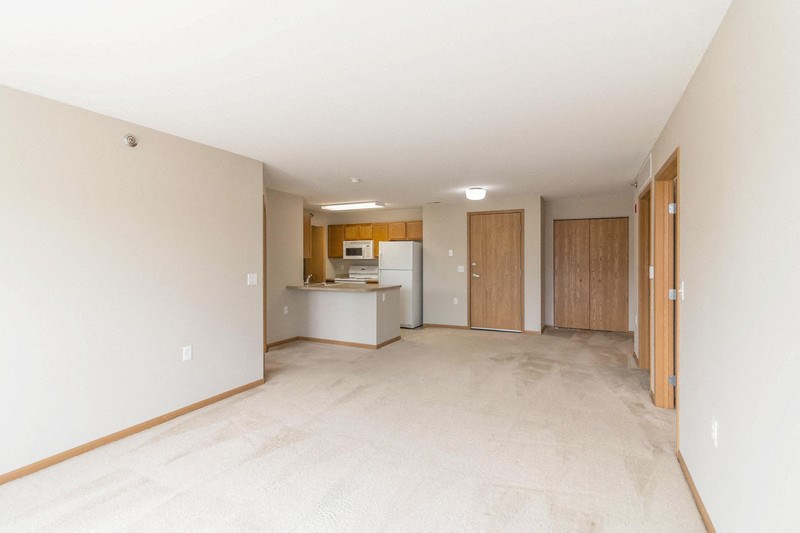 the living room and kitchen of an empty house with white walls and tile flooring