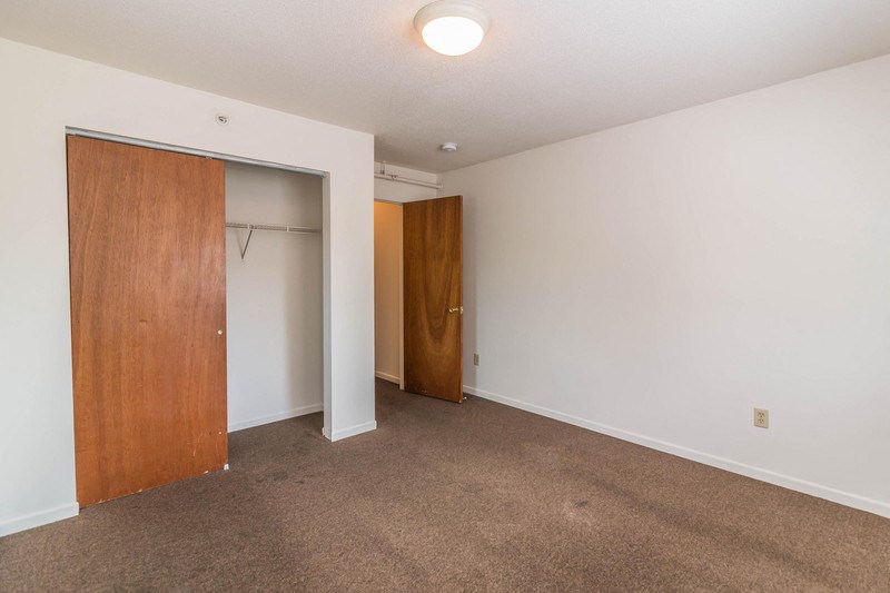a bedroom with a door to a closet and a carpeted floor