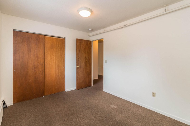a bedroom with a carpeted floor and a door to a hallway