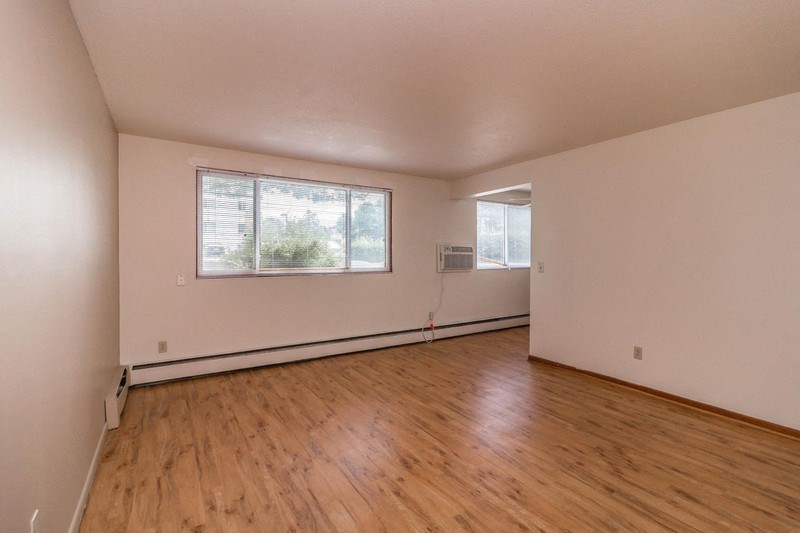 the living room of an empty house with wood floors and a window