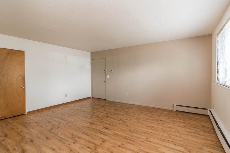an empty living room with wood floors and a door