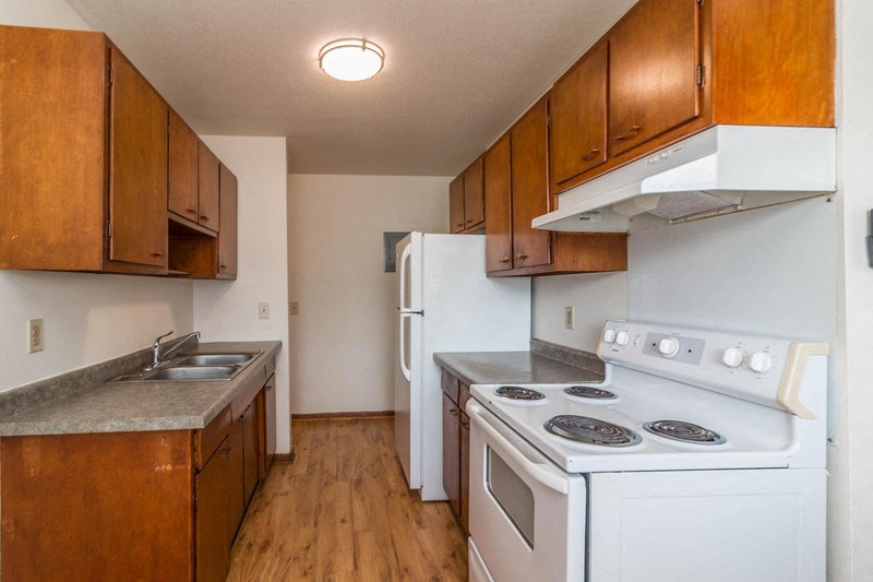 an empty kitchen with white appliances and wooden cabinets