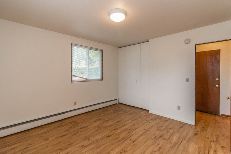 a living room with wood floors and white walls and a window
