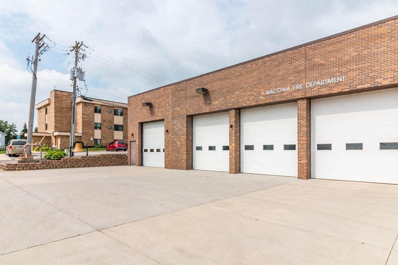 a brick building with white garage doors and a parking lot
