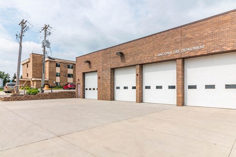 a brick building with white garage doors and a parking lot