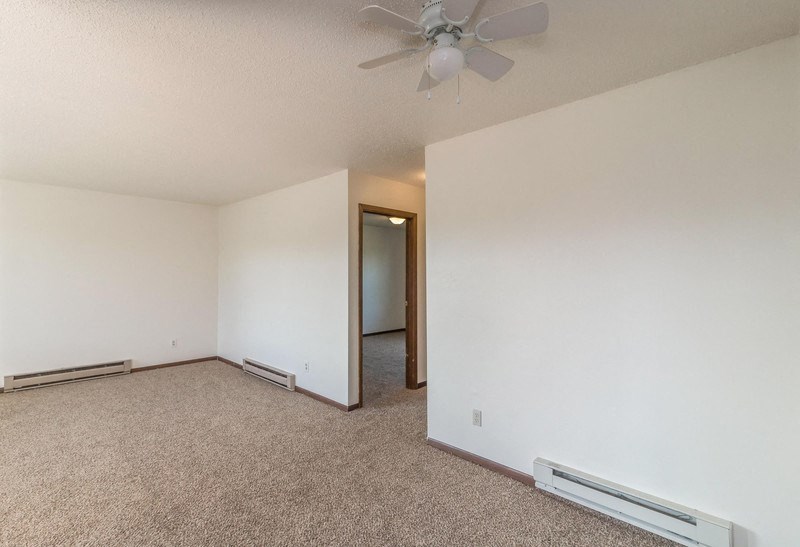 the living room of an empty apartment with a ceiling fan
