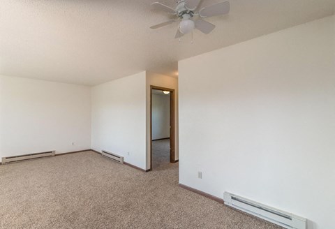the living room of an empty apartment with a ceiling fan