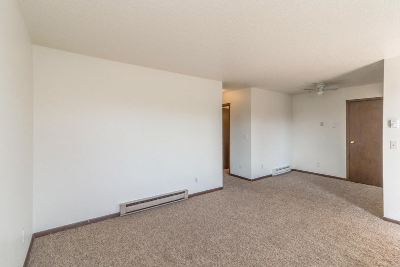an empty living room with white walls and carpet