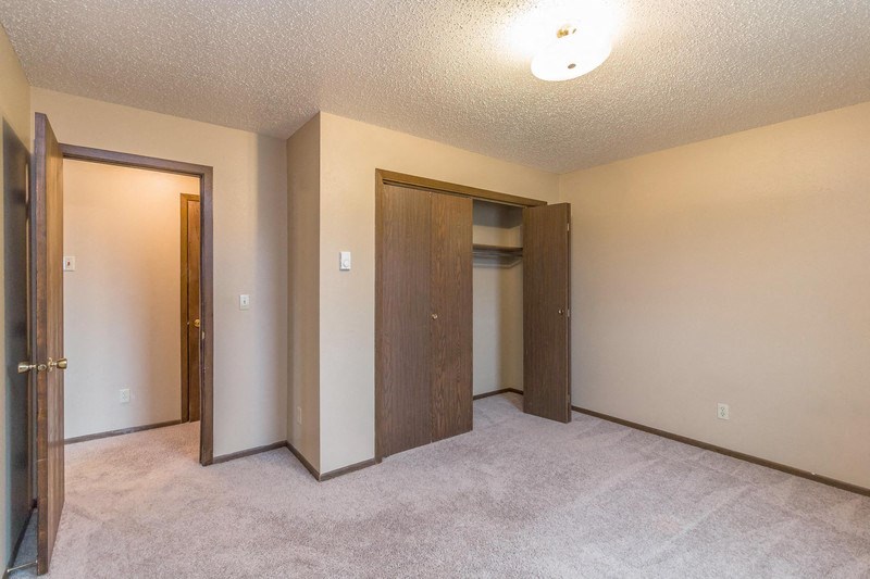 an empty bedroom with two doors and a closet
