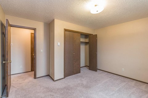 an empty bedroom with two doors and a closet
