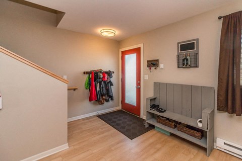 the entrance to a house with a closet and a red door
