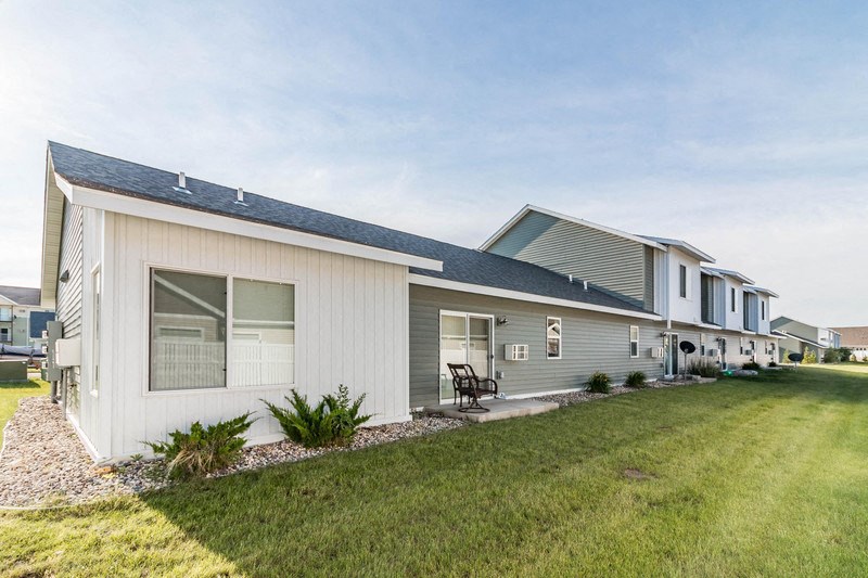 the front of a white and gray house with grass and a lawn