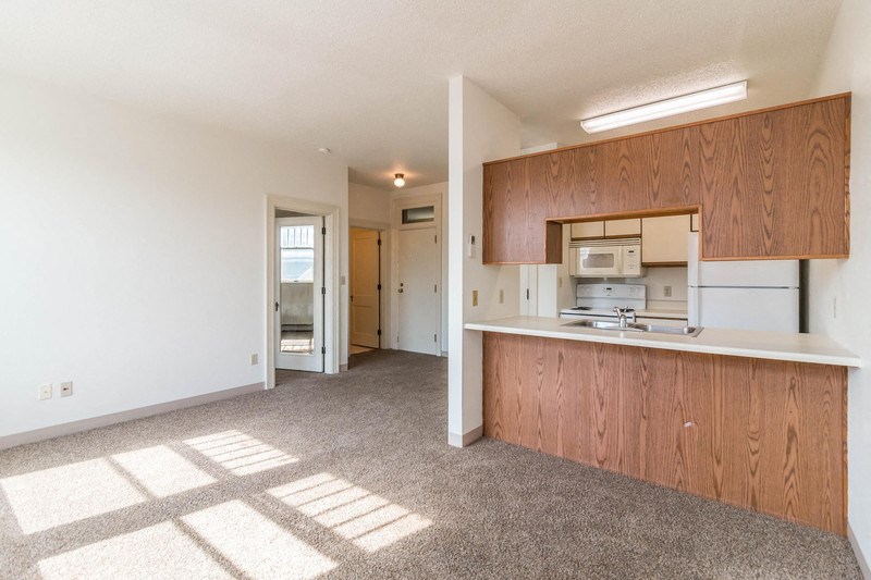 an empty kitchen with wood cabinets and a white counter top
