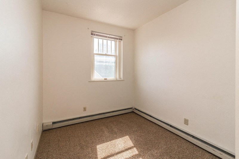 an empty room with a window and carpet
