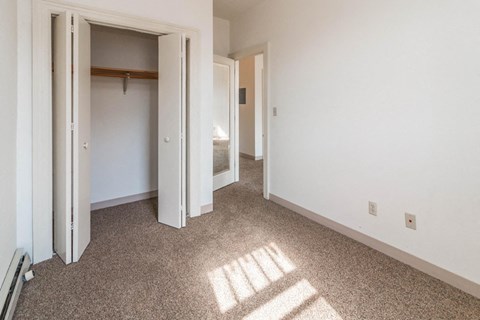 an empty room with a hallway to a bedroom and a closet