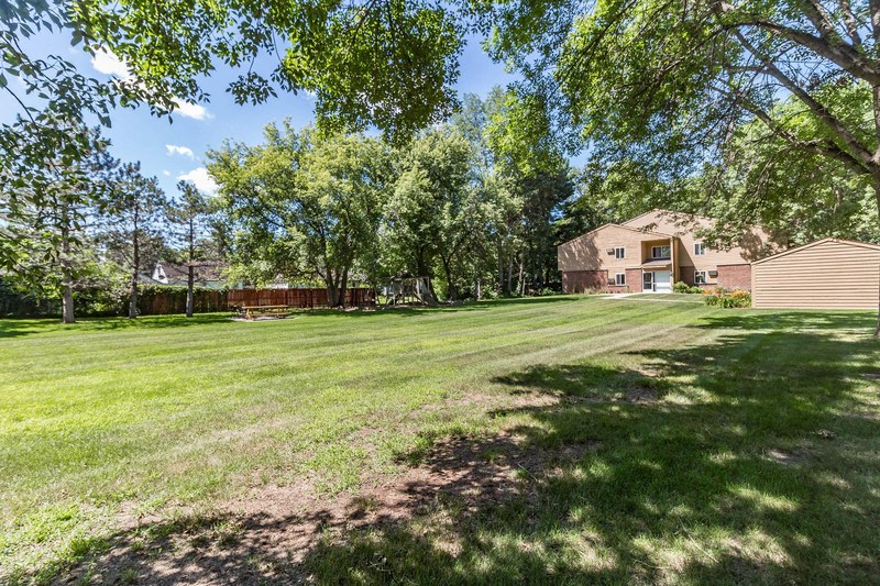 a large yard with trees and a house in the background