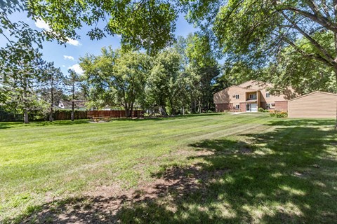 a large yard with trees and a house in the background