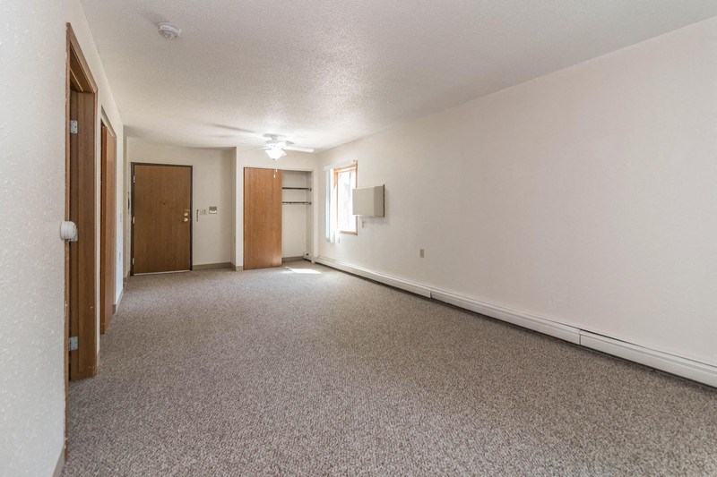 the living room and dining room of an empty house with carpeting and a door