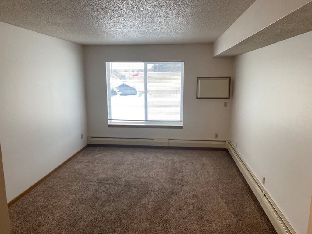 an empty room with a window and a carpet