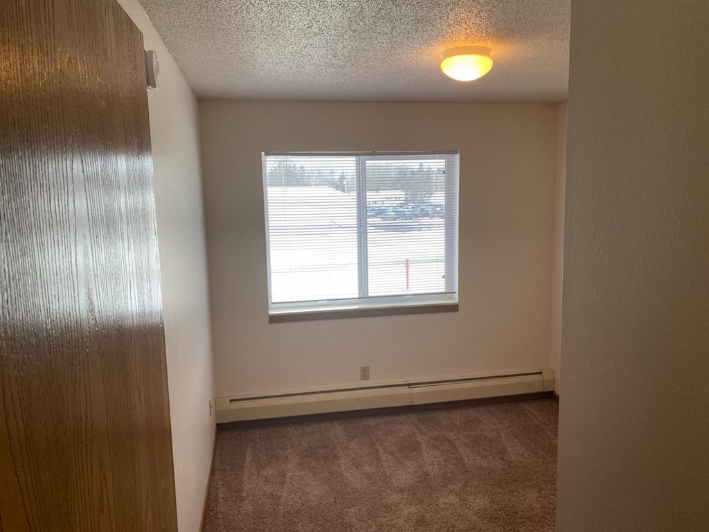 a bedroom with a window and a carpeted floor