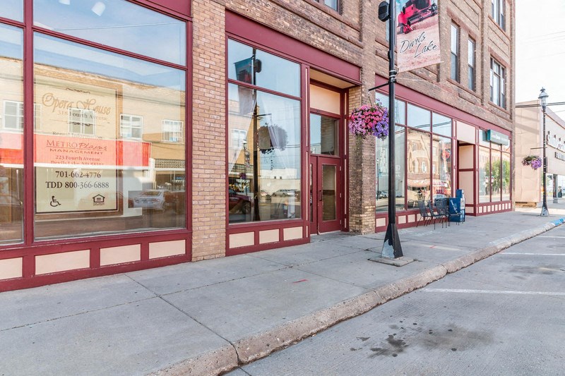 a city sidewalk in front of a brick building with glass windows