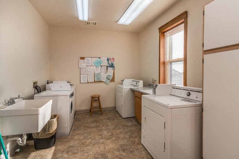 a laundry room with two washing machines and a sink and a window