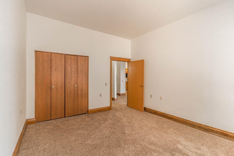 a empty living room with carpet and a door to a hallway
