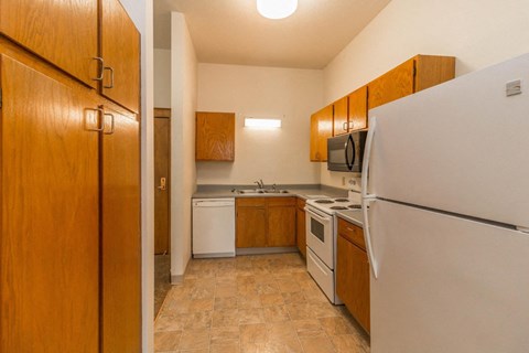 a kitchen with white appliances and wooden cabinets and a refrigerator