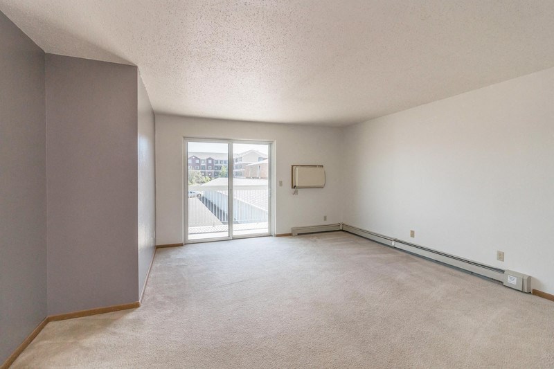 the living room of an empty apartment with a door to the balcony