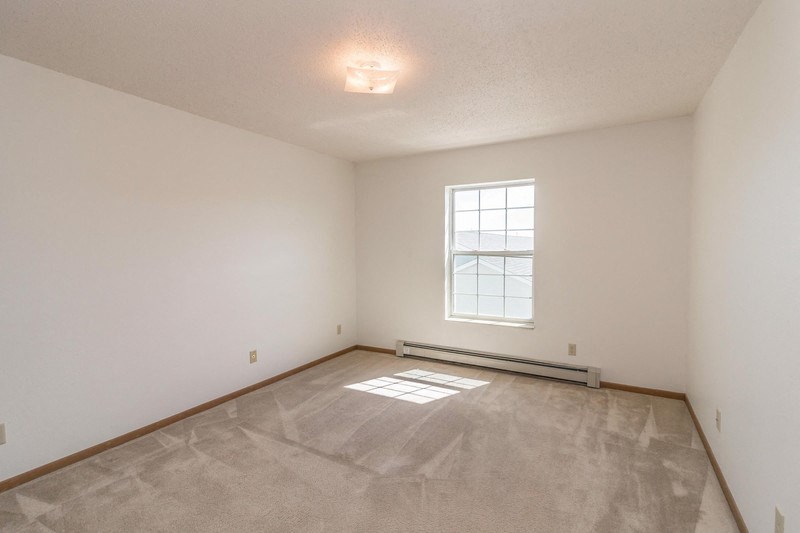 the spacious living room with white walls and a window
