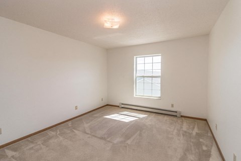 the spacious living room with white walls and a window