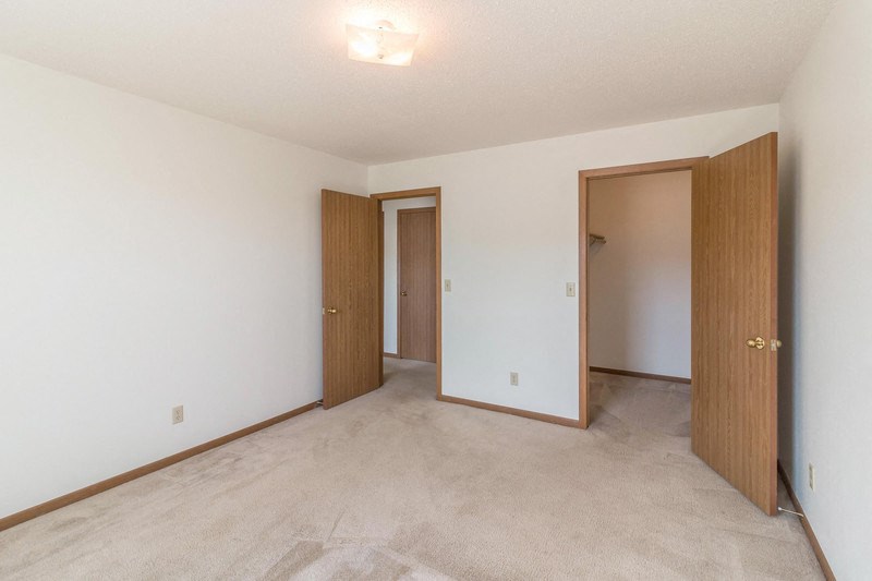 the living room and bedroom of an empty house with two doors