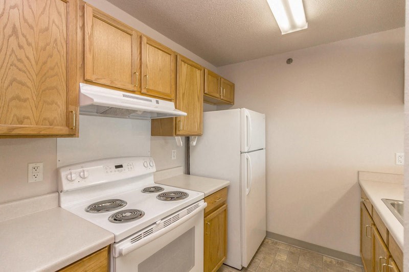a kitchen with white appliances and wooden cabinets and a refrigerator