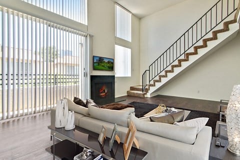 A modern living room with a staircase and a television.