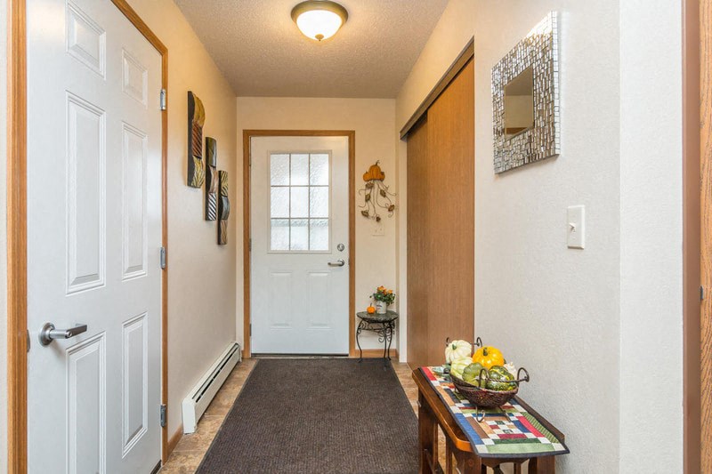 the hallway of a home with a white door and a table