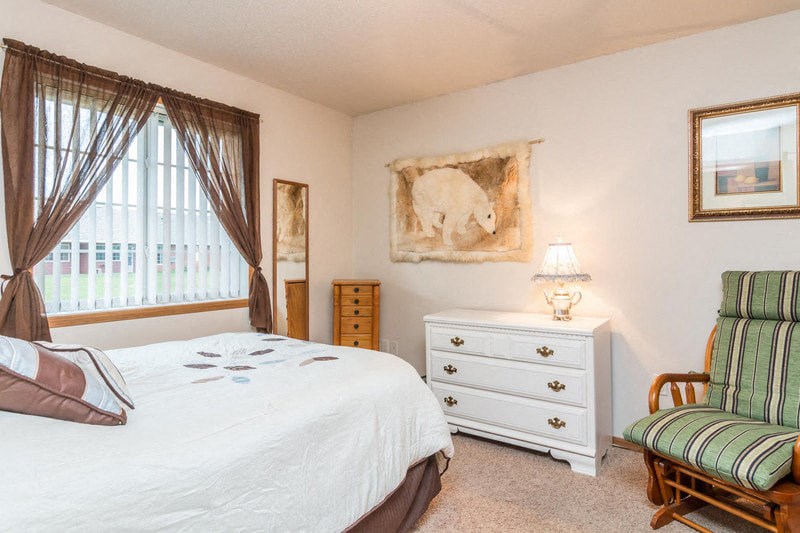 a bedroom with a bed and a chair and a window